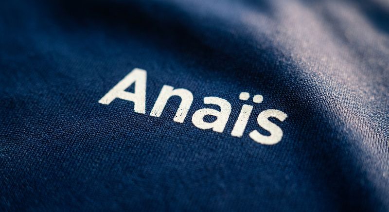 Le prénom « Anaïs » à l'encre claire sur un polyester marine légèrement satiné.